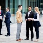 Well dressed executives conversing in groups outside of office building